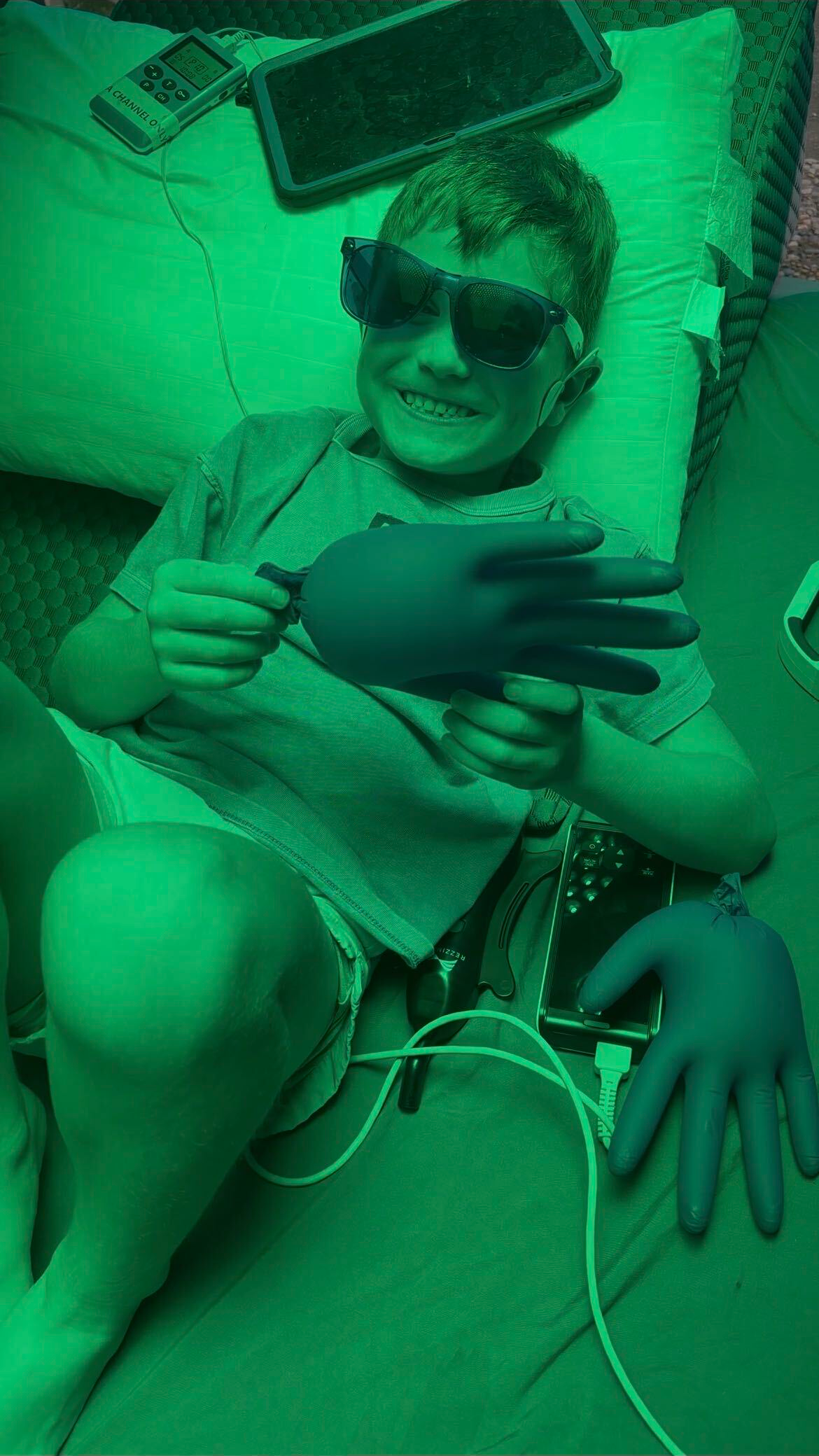 A person lying back on a padded table, smiling, in a room lit in green.